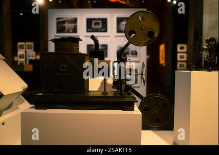 Proiettore cinematografico antico esposto in un museo con fotografie d'epoca sullo sfondo. L'attrezzatura cinematografica di vecchio stampo mette in risalto l'HIS Foto Stock
