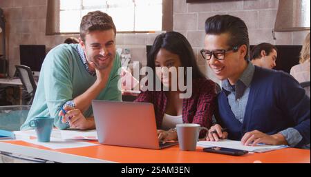 Tre designer in Creative Business che utilizzano laptop Meeting in un moderno ufficio multiculturale Foto Stock