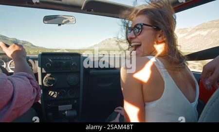 Primo piano di una giovane coppia durante il viaggio in auto cabriolet lungo Country Road Foto Stock