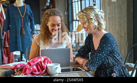 Due stilisti di moda femminili in Studio che lavorano insieme su un laptop Foto Stock