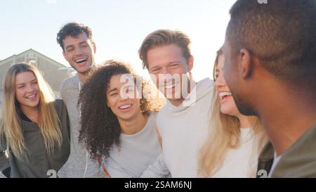 Gruppo di giovani amici all'aperto che parlano e ridono insieme Foto Stock