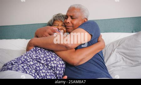 Una coppia anziana amorevole a casa coccola a letto al mattino Foto Stock