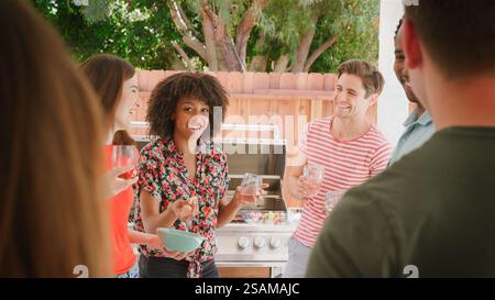 Gruppo di giovani amici sorridenti che si godono un drink estivo all'aperto nel Garden at Home Foto Stock