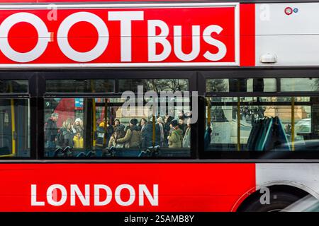 AUTOBUS TOOT che passa accanto ai turisti di Londra. La folla di persone è raggruppata intorno alla loro Guida. Foto interessante mentre vedi la gente attraverso il bus. Foto Stock