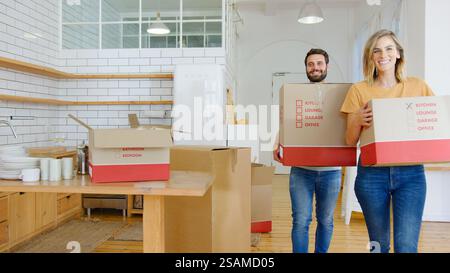 Una giovane coppia sorridente che porta scatole da imballaggio in New Home Foto Stock