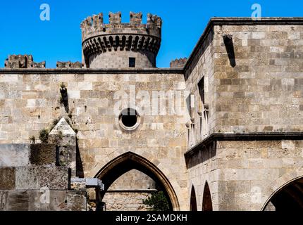 Una vista ravvicinata dell'antica architettura in pietra caratterizzata da una torre del castello e mura. La struttura presenta intricati lavori in pietra sotto un cielo azzurro. Foto Stock