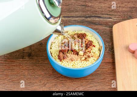 Versare acqua bollita sugli spaghetti istantanei. Fast food. Foto Stock