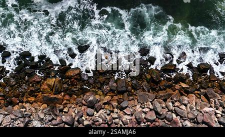 Onde oceaniche verdi e limpide che colpiscono la costa rocciosa Foto Stock