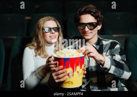 La coppia si diverte a guardare un film insieme a popcorn e bicchieri 3D. Foto Stock