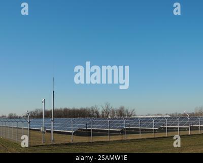 pannelli solari nel campo agricolo dietro recinzione a reticolo con telecamera di sorveglianza nelle giornate di sole, apparecchiature di ricezione dell'energia solare presso la stazione Foto Stock