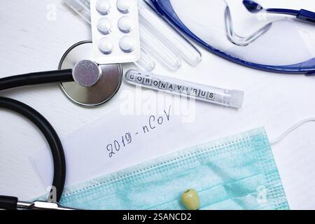 Vari articoli medici e una provetta da 2019 nCoV etichettata su un tavolo Foto Stock