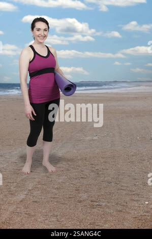 Bella donna che porta con sé un tappetino da yoga prima di fare esercizio fisico Foto Stock