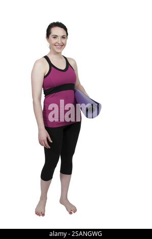 Bella donna che porta con sé un tappetino da yoga prima di fare esercizio fisico Foto Stock