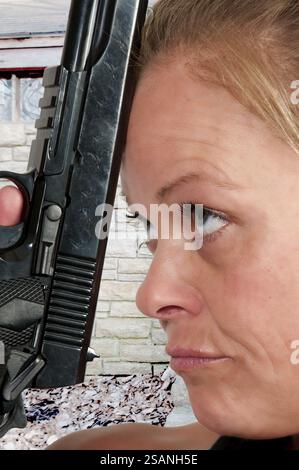 Donna che tiene una pistola alla testa che minaccia il suicidio Foto Stock