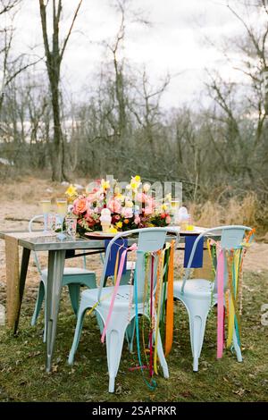 Un affascinante tavolo all'aperto e' adornato con una vibrante disposizione floreale e decorazioni colorate, a mettere in risalto un'atmosfera gioiosa. Le funzioni di impostazione Foto Stock