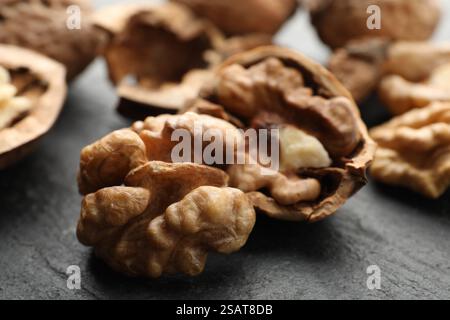 Noci mature fresche e conchiglie sul tavolo nero, primo piano Foto Stock