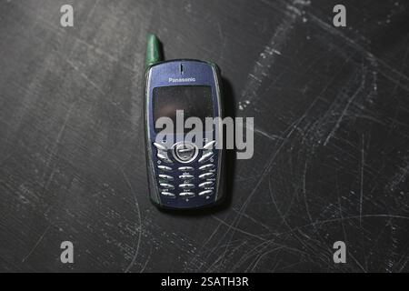 Primo piano di un telefono cellulare Panasonic blu con antenna su una superficie scura Foto Stock
