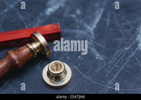 Guarnizione in ottone con cera rossa su sfondo scuro testurizzato Foto Stock