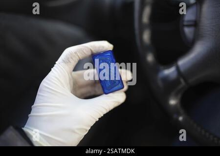 Mano con guanti che reggono un chip blu all'interno dell'abitacolo Foto Stock