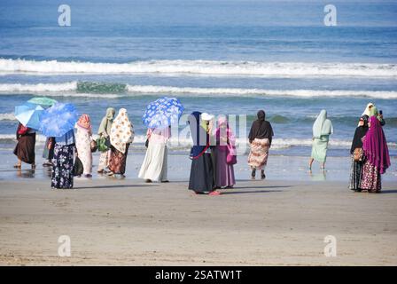 Donne che guardano il mare sulla spiaggia di Kuta, Bali, vestite con abiti tradizionali Foto Stock