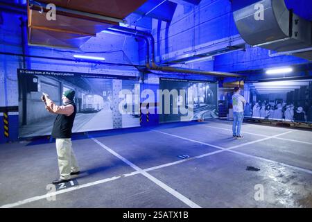 Persone nei vecchi tunnel abbandonati della stazione di Wynyard sotto Sydney, Australia, che guardano una mostra di foto storiche Foto Stock