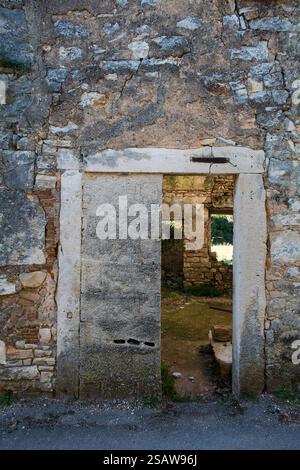 Una porta aperta, parzialmente bloccata da una lastra di cemento, in una casa abbandonata nel villaggio storico di Svetvincenat nel cuore dell'Istria, Croazia. Foto Stock