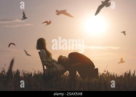 Una coppia avvolta dalla luce del tramonto scambia gesti d'amore in un campo Foto Stock