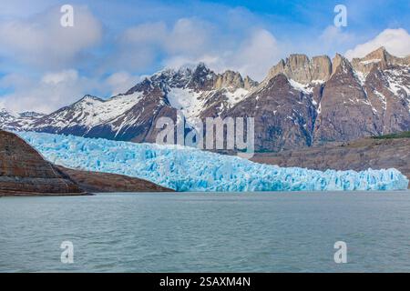 Vista lontana del Ghiacciaio Grigio che scorre nel Lago Grey circondato dalle montagne di Torres del Paine durante il giorno Foto Stock
