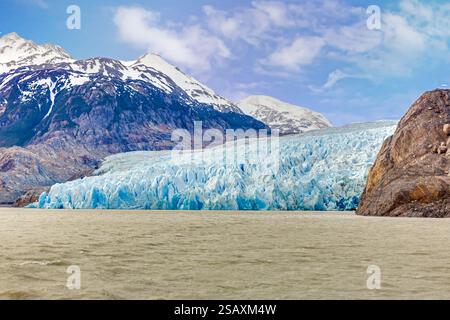 Vista lontana del Ghiacciaio Grigio che scorre nel Lago Grey circondato dalle montagne di Torres del Paine durante il giorno Foto Stock