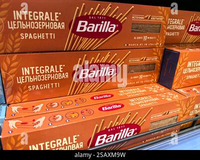 Bobruisk, Bielorussia - 26 gennaio 2025: Confezioni colorate di spaghetti integrali di grano fiancheggiano gli scaffali in un negozio di alimentari affollato. Gli acquirenti esplorano la varietà Foto Stock