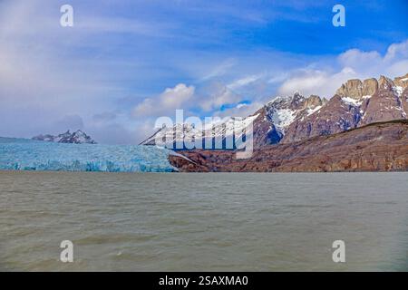 Vista lontana del Ghiacciaio Grigio che scorre nel Lago Grey circondato dalle montagne di Torres del Paine durante il giorno Foto Stock