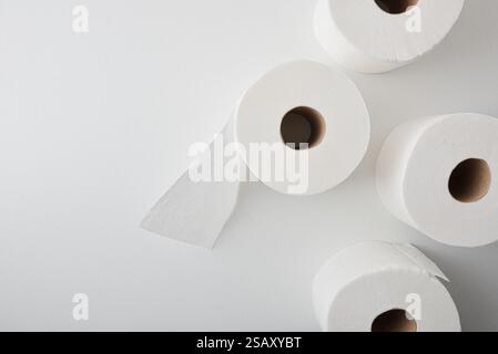 Fondo con quattro rotoli di carta igienica bianca perforata, isolati su un tavolo bianco. Vista dall'alto. Foto Stock