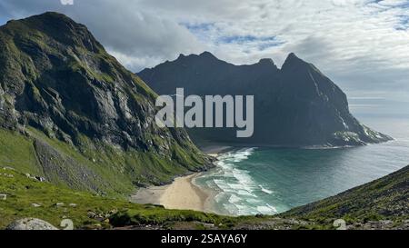 Una vista aerea mozzafiato di Kvalvika Beach, Norvegia, dove le onde turchesi si incontrano con le sabbie dorate circondate da imponenti cime montuose. Foto Stock