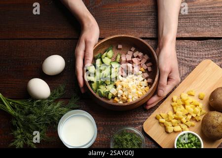 Donna che prepara zuppa di okroshka al tavolo di legno, vista dall'alto Foto Stock Donna che prepara zuppa di okroshka al tavolo di legno, vista dall'alto Foto Stock