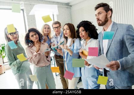 Brainstorming di gruppi professionali diversi in ufficio con appunti appiccicosi su una parete in vetro Foto Stock