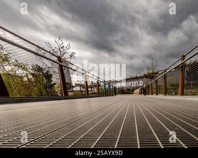 Una vista dall'angolazione bassa rivela l'impressionante Depot Mayfield sotto un suggestivo cielo grigio, mettendo in risalto il design urbano e la natura circostante. Foto Stock