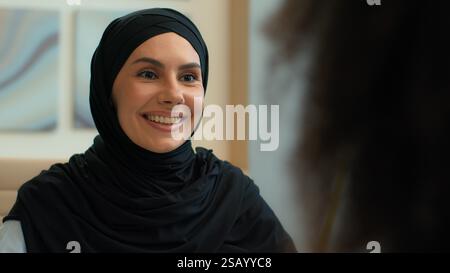 Donna d'affari araba felice sorridente ragazza islamica musulmana donna in hijab manager consulente venditore agente immobiliare che parla riunione di ufficio di un cliente femminile Foto Stock