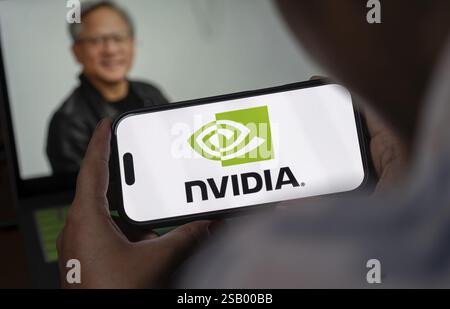 In questa illustrazione fotografica, il logo Nvidia Corporation viene visualizzato su uno schermo iPhone davanti alla foto del CEO di Nvidia Jensen Huang su Jan Foto Stock
