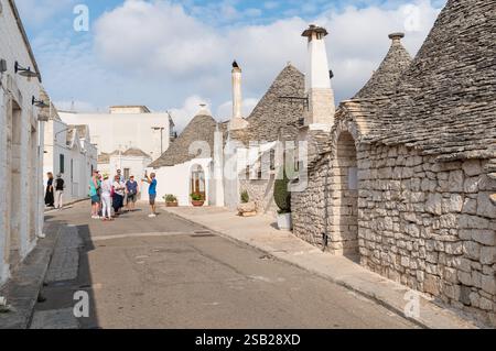 Alberobello, Puglia, Italia - 5 ottobre 2023: Turisti che visitano le case calcaree dei trulli nell'antico borgo di Alberobello, in provincia di Foto Stock