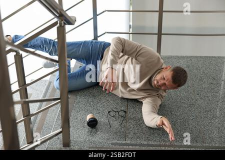Uomo ferito sulle scale dell'edificio dopo la caduta. Incidente pericoloso Foto Stock
