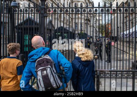 Londra, Regno Unito - 8 aprile 2024: Turisti che guardano attraverso i cancelli e la sicurezza all'ingresso di Downing Street a Londra, Regno Unito. Downing Street è la r Foto Stock