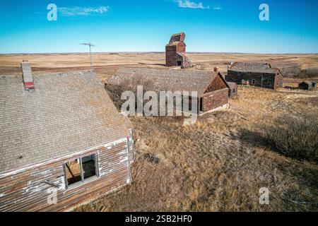 Una casa con un camino e' nel mezzo di un campo. Ci sono altre case sullo sfondo Foto Stock
