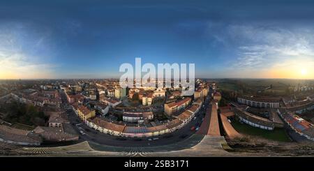 Scatto panoramico con drone che cattura il paesaggio urbano di Cremona durante un sereno tramonto invernale, mostrando la bellezza architettonica e il layout urbano della città Foto Stock