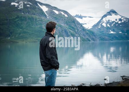 Foto tonificata di un giovane che contempla un lago e montagne in Alaska Foto Stock