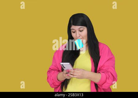 La donna latina di 30 anni usa la sua carta di credito e il cellulare per effettuare acquisti e pagamenti online, approfittare di promozioni e sconti Foto Stock