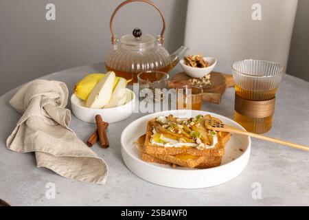 Colazione con toast al formaggio spalmabile e pere caramellate, miele e noci Foto Stock
