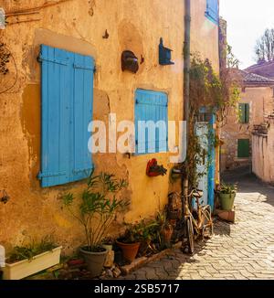 Bicicletta contro il muro giallo di una casa, nel villaggio di Lautrec, a Tarn, Occitanie, Francia Foto Stock
