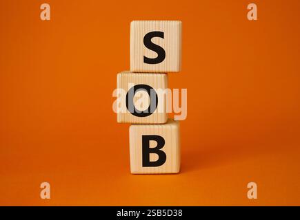 SOB - simbolo respiro corto. Cubi di legno con parole SOB. Bellissimo sfondo arancione. Concetto medico e SOB. Copia spazio. Foto Stock