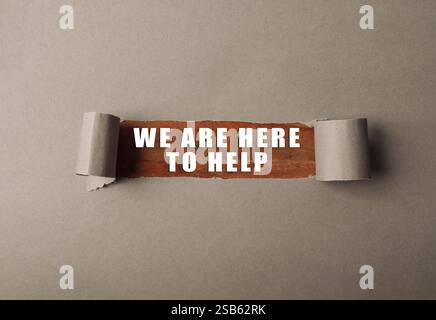 Strappato un pezzo di carta con le parole che siamo qui per aiutare a scrivere su di esso. L'immagine ha un senso di urgenza e un invito all'azione Foto Stock