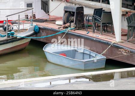 una piccola barca ormeggiata al molo. La barca è di colore grigio e ha un tetto bianco. Foto Stock